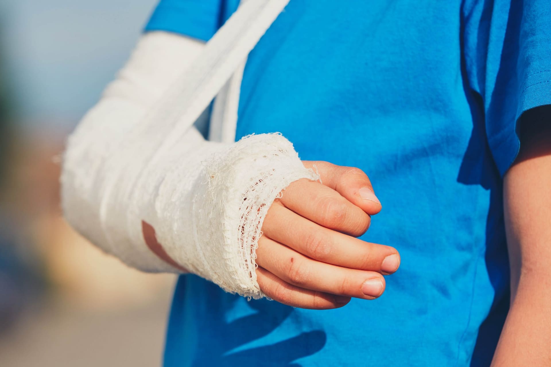 Kind met een verband om hand en pols in een mitella