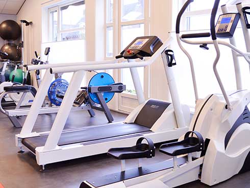 De oefenzaal met loopband, crosstrainer en fitnessapparatuur
